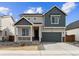 Two-story home featuring a charming front porch, gray siding, well-manicured landscaping, and an attached two-car garage at 190 Lark Sparrow Way, Bennett, CO 80102