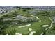 Aerial view of a meticulously maintained golf course with ponds, sand traps, and vibrant green fairways at 6153 N Ceylon St # 104, Denver, CO 80249