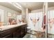 Bathroom with double sink vanity and shower with decorative floral pattern curtain at 13673 Valentia St, Thornton, CO 80602