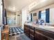 Bathroom featuring double sinks, framed mirrors, and a glass door shower at 13673 Valentia St, Thornton, CO 80602