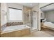 Modern bathroom featuring a soaking tub and separate shower with glass enclosure and travertine tile at 10273 Nottingham Dr, Parker, CO 80134