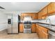 Charming kitchen featuring stainless steel appliances, oak cabinets, and tile floors at 6721 Quay Ct, Arvada, CO 80003