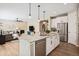 Open kitchen with island seating, stainless steel appliances, and view into the living room with fireplace at 9446 E 51St Dr, Denver, CO 80238