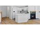 Modern all-white kitchen with stainless appliances, ample countertop space, and a cozy fireplace at 14247 Pikeminnow Pl, Broomfield, CO 80023