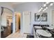 Bathroom featuring a dual sink vanity with black countertop and access to an additional room with white tile flooring at 9624 Crosspointe Dr, Highlands Ranch, CO 80130