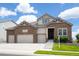 Two-story house with stone and beige siding, three-car garage, and landscaped yard at 15994 La Plata Peak Pl, Broomfield, CO 80023