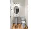 A powder bathroom featuring a pedestal sink, oval mirror, toilet, and hardwood floors at 4511 Perry St, Denver, CO 80212