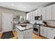 Open kitchen with a center island, white cabinets, stainless steel appliances, granite countertops, and wooden floors at 4511 Perry St, Denver, CO 80212