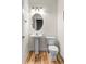 Charming powder room with pedestal sink, oval mirror, modern lighting and wood flooring at 4511 Perry St, Denver, CO 80212