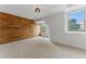 Bedroom with a striking wood accent wall, plush carpet, and double-paned windows at 2011 S Gray Dr, Lakewood, CO 80227