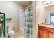 Bright bathroom featuring a shower/tub combo with a decorative teal and white curtain and wood vanity at 22920 E Roxbury Dr # H, Aurora, CO 80016
