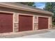 Three-car garages with a burgundy door, stone accents, and neutral-colored walls at 22920 E Roxbury Dr # H, Aurora, CO 80016