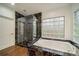 Modern bathroom featuring a glass-enclosed shower, soaking tub, and black marble accents at 5631 Silver Bluff Ct, Parker, CO 80134