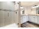 Bright bathroom showcasing tiled shower, double sinks with granite counters and wood-look floor at 410 Clover Ct, Frederick, CO 80530