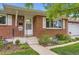 Inviting front porch with brick facade, concrete steps, and manicured landscaping adds curb appeal at 7901 E Kenyon Dr, Denver, CO 80237