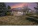 Charming backyard featuring mature trees, lush greenery, a stone patio, and a well-maintained lawn at 13806 E Chenango Dr, Aurora, CO 80015