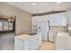 Well-lit kitchen featuring an island cooktop, white cabinetry, and modern appliances at 13806 E Chenango Dr, Aurora, CO 80015