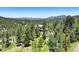 Wide aerial shot showcasing the home nestled amongst trees with mountain views at 30889 Manitoba Dr, Evergreen, CO 80439