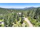 Distant aerial view of beautiful home surrounded by a dense forest and rolling hillsides at 30889 Manitoba Dr, Evergreen, CO 80439