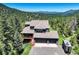 Aerial view of stunning blue home nestled amongst lush greenery with a large garage at 30889 Manitoba Dr, Evergreen, CO 80439