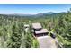 Scenic aerial view of home nestled amongst a forest with rolling hillsides at 30889 Manitoba Dr, Evergreen, CO 80439