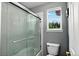 Modern bathroom featuring a glass-enclosed shower, toilet, and window with natural light, creating a serene atmosphere at 30889 Manitoba Dr, Evergreen, CO 80439