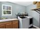 Well-lit laundry room featuring modern washer and dryer units, complemented by functional storage shelves and a sink area at 30889 Manitoba Dr, Evergreen, CO 80439