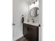 A modern powder room with a dark wood vanity, white countertop, and a round mirror at 4184 Kalamath St, Denver, CO 80211