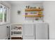 Laundry area with modern washer and dryer, floating shelves, and natural light at 2075 Oakland St, Aurora, CO 80010