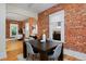 Open-concept dining room with brick accent wall, wood floors, and a view into the living area at 2527 W Dunkeld Pl, Denver, CO 80211