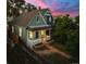 Charming home featuring a covered front porch, brick garden beds, and walkway, framed by mature trees at dusk at 2527 W Dunkeld Pl, Denver, CO 80211