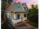 Charming home featuring a covered front porch, brick garden beds, and walkway, framed by mature trees at dusk at 2527 W Dunkeld Pl, Denver, CO 80211