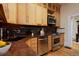 Well-lit kitchen with granite countertops, modern appliances, wood cabinets, and tile backsplash at 2527 W Dunkeld Pl, Denver, CO 80211
