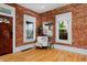 Charming living room featuring exposed brick walls, hardwood floors, and natural light from two windows at 2527 W Dunkeld Pl, Denver, CO 80211