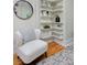 Inviting sitting area with a cozy chair, round mirror, and built-in shelving with decorative items at 2527 W Dunkeld Pl, Denver, CO 80211