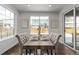 Dining area with a rectangular table, tufted chairs, hardwood floors and natural light from large windows at 14769 Dahlia St, Thornton, CO 80602