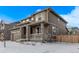 Two-story home showcasing stone accents and a cozy front porch in a winter landscape at 14769 Dahlia St, Thornton, CO 80602