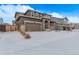 Front exterior shows a two-car garage, stone details, covered porch and snow covered driveway and yard at 14769 Dahlia St, Thornton, CO 80602