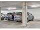 Parking garage featuring multiple parked cars, concrete pillars, and overhead lighting at 1200 Cherokee St # 106, Denver, CO 80204