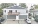 A two-story home features a garage, small porch, and green and gray paint with a background of green trees at 10001 E Evans Ave # D, Aurora, CO 80247