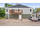 Two-story apartment exterior with dual garage doors and a balcony over the entryway, painted in gray and green at 10001 E Evans Ave # D, Aurora, CO 80247