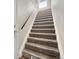 Staircase with carpeted steps and white walls. Features a black handrail at 10001 E Evans Ave # D, Aurora, CO 80247