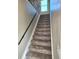 Carpeted stairway with a black railing leads upstairs, illuminated by a window at the top at 10001 E Evans Ave # D, Aurora, CO 80247