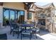 Inviting outdoor patio featuring a stone fireplace, dining table, and sliding doors with mountain views at 5650 E Stanford Dr, Cherry Hills Village, CO 80111