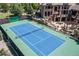Aerial view of a well-maintained tennis court with lush landscaping and a beautiful home in the background at 5650 E Stanford Dr, Cherry Hills Village, CO 80111