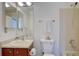 Bright bathroom featuring a neutral-toned shower, white toilet and sink with vanity, and a mirrored medicine cabinet at 10359 W Fair Ave # F, Littleton, CO 80127