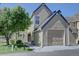 Image of a charming two-story home featuring a two-car garage, with green lawn and mature tree at 10359 W Fair Ave # F, Littleton, CO 80127