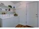 Well-lit laundry room featuring white appliances, storage shelves, and a white door at 10359 W Fair Ave # F, Littleton, CO 80127