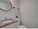 Small powder room with granite-look vanity, neutral walls, and round mirror at 10359 W Fair Ave # F, Littleton, CO 80127