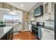 Bright kitchen features a farmhouse sink, granite counters, tree wallpaper, and updated appliances at 2190 Helen Ct, Parker, CO 80138